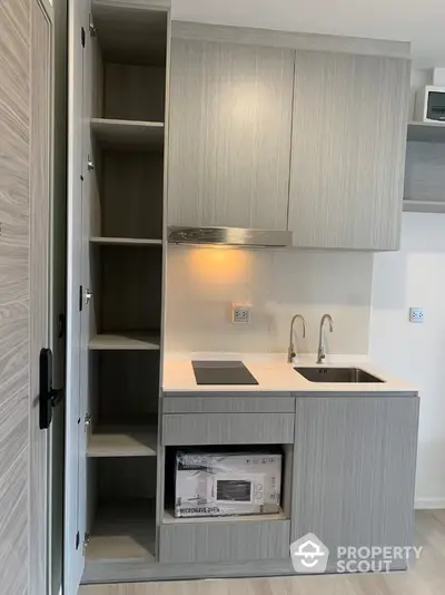 Modern compact kitchen with sleek cabinetry and built-in microwave