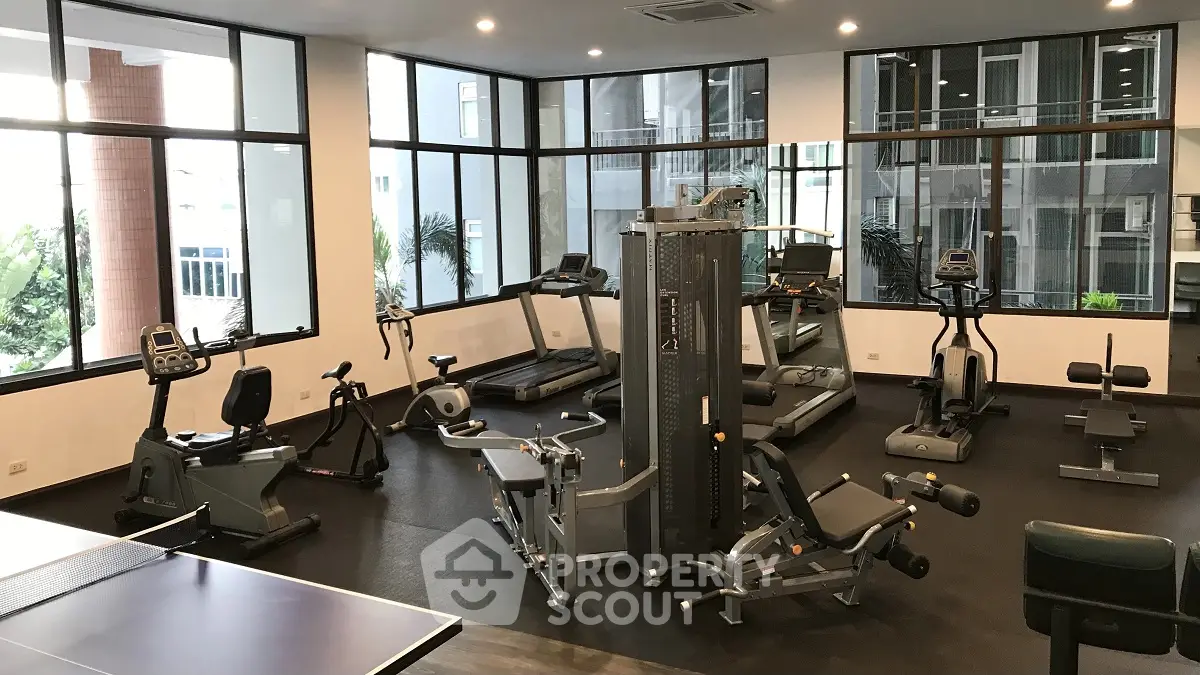 Modern gym with state-of-the-art fitness equipment and large windows in a residential building.
