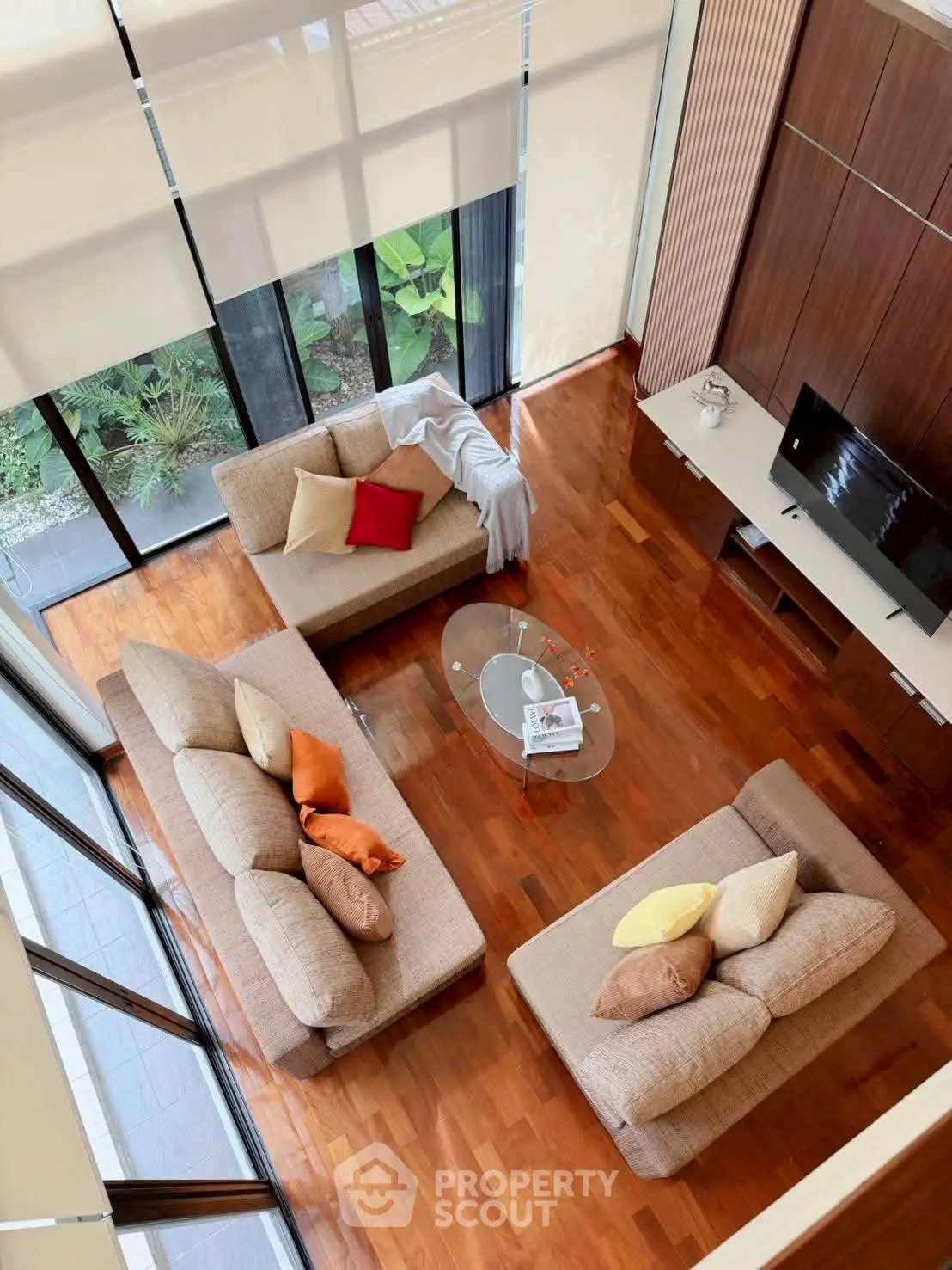 Spacious modern living room with elegant furniture and large windows offering garden views.