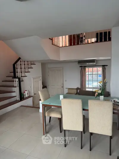 Spacious modern dining area with elegant staircase and natural light