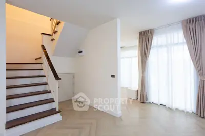 Spacious modern living area with elegant staircase and large windows