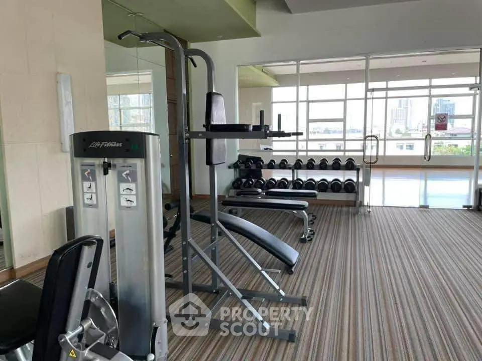 Spacious gym with modern fitness equipment and city view, perfect for active lifestyle enthusiasts.