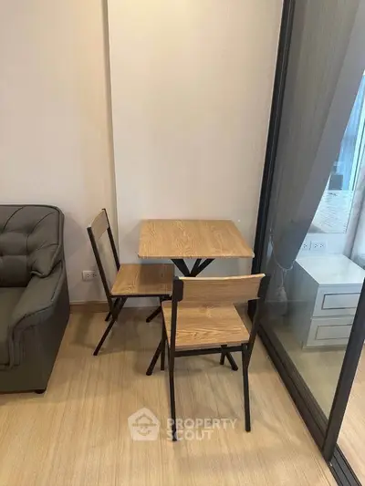 Cozy corner with wooden table and chairs next to a glass door in a modern apartment.