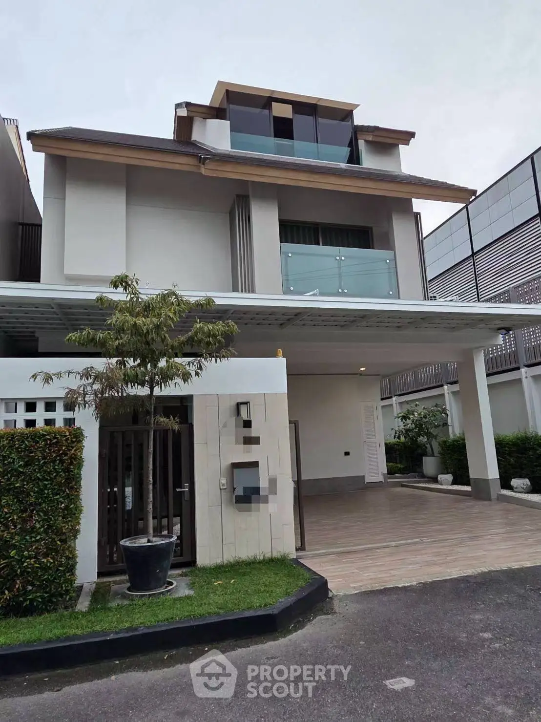 Modern multi-story house with spacious driveway and sleek balcony design.