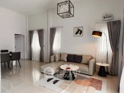 Modern living room with stylish decor and dining area, featuring elegant furniture and natural light.