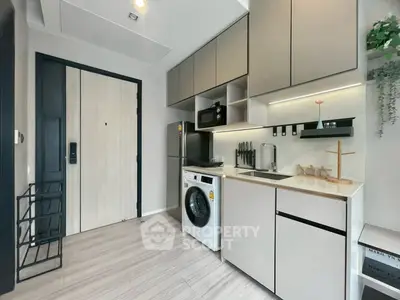 Modern compact kitchen with washing machine and sleek cabinetry in stylish apartment.