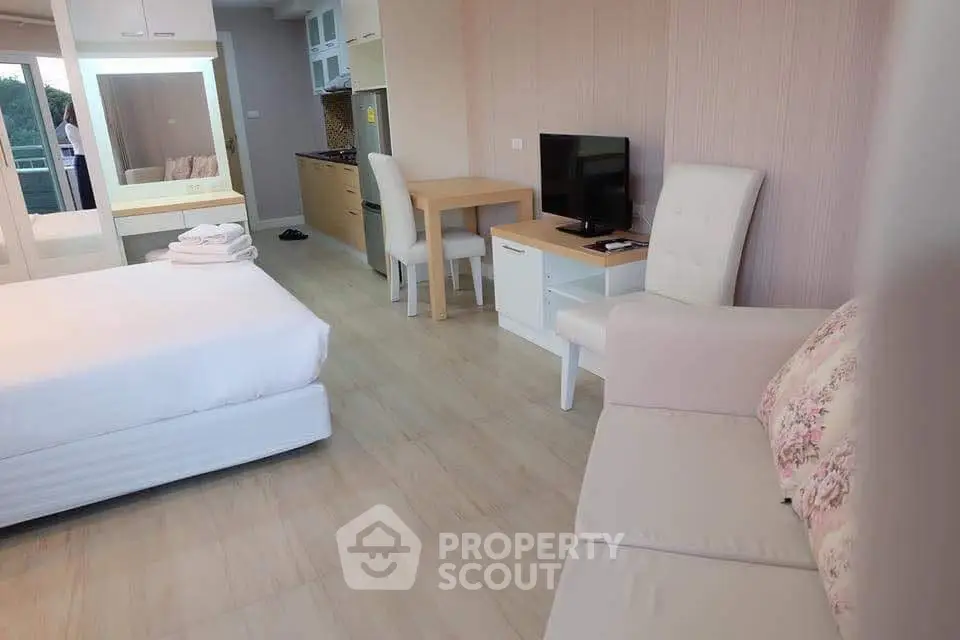 Modern studio apartment with cozy living area and kitchenette, featuring elegant furniture and natural light.