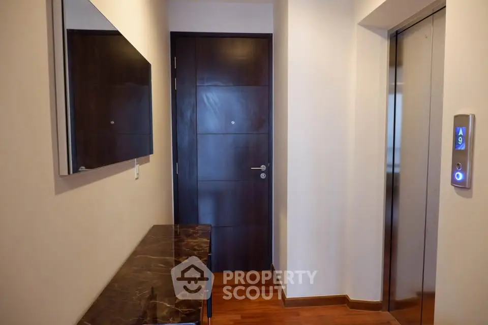 Modern apartment entrance with elevator access and elegant wooden flooring.