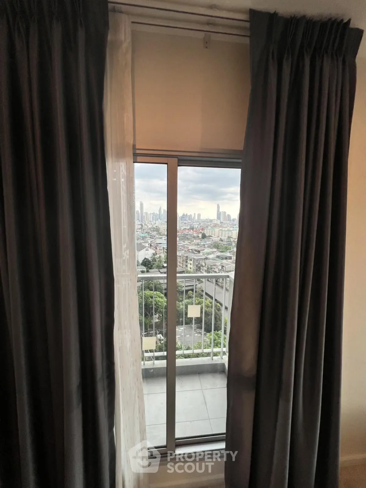 Stunning cityscape view from a cozy apartment balcony, framed by elegant curtains.