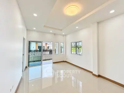 Spacious modern living room with large windows and balcony access, featuring sleek lighting and glossy tiled floors.