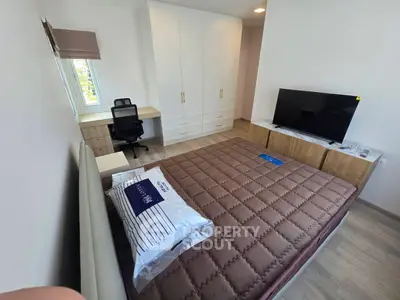 Modern bedroom with large wardrobe, desk, and flat-screen TV, perfect for comfortable living.