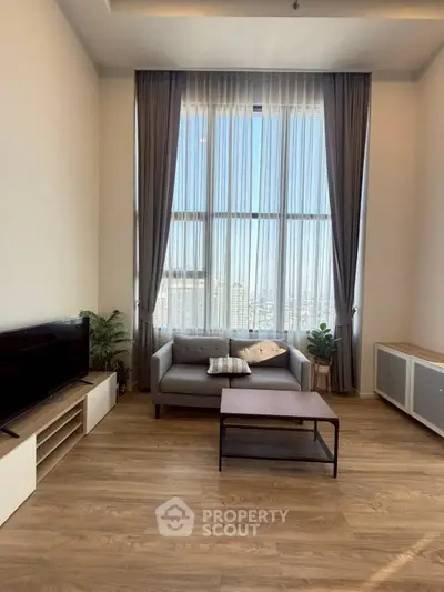 Spacious living room with high ceilings and large windows offering a stunning city view.