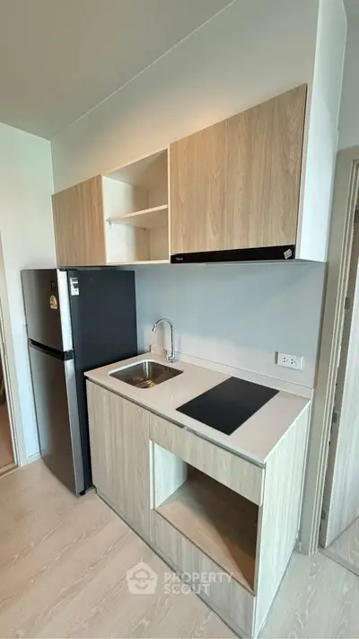 Modern compact kitchen with sleek cabinetry and built-in appliances in a stylish apartment.