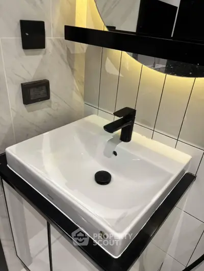 Modern bathroom sink with sleek black fixtures and ambient lighting