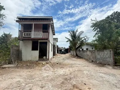 Charming two-story rustic house with spacious driveway and lush greenery, perfect for serene living.