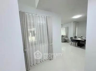 Modern open-layout living and dining area with elegant curtains and sleek furniture.