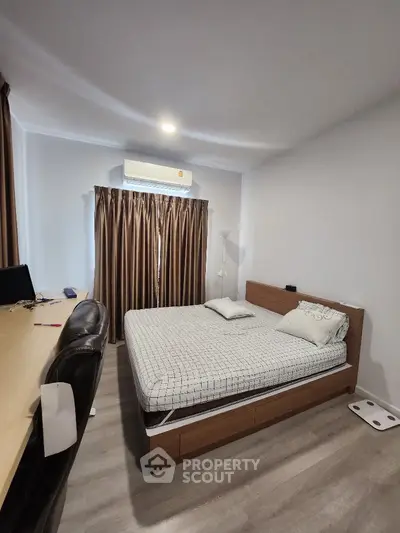 Spacious bedroom with modern furnishings, including a large bed, sleek desk, and air conditioning, perfect for comfort and productivity.