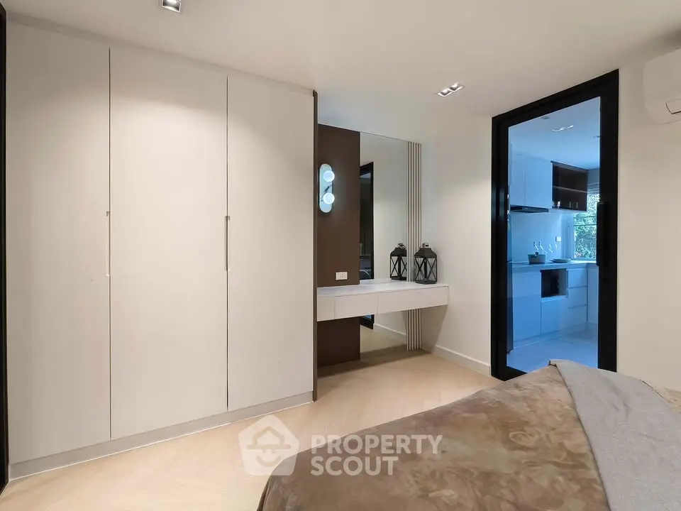 Modern bedroom with sleek wardrobe and view into a contemporary kitchen