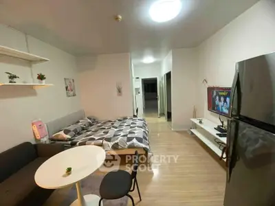 Modern studio apartment with cozy living area and sleek kitchen appliances.