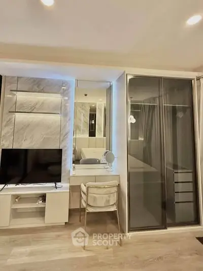 Modern bedroom with sleek design, featuring a TV unit, mirrored vanity, and sliding wardrobe doors.