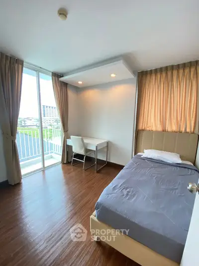 Modern bedroom with balcony view, featuring sleek wooden flooring and cozy study area.