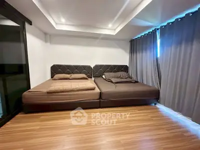 Spacious bedroom with modern design and twin beds, featuring elegant lighting and wooden flooring.