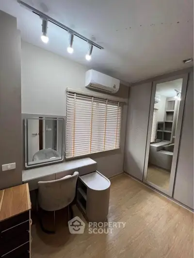 Modern bedroom with sleek vanity and mirrored wardrobe, featuring stylish lighting and wooden flooring.