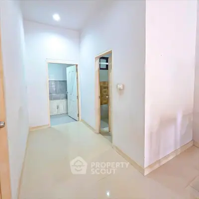 Bright hallway with glossy tiled floors leading to multiple rooms in a modern apartment.