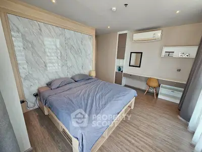 Modern bedroom with stylish decor and natural light, featuring a comfortable bed and workspace.