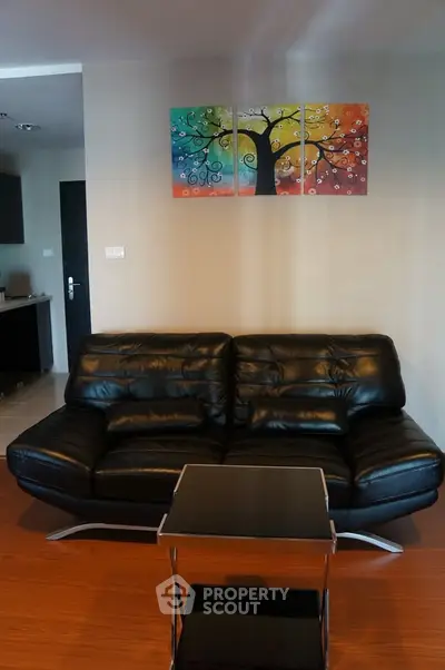 Modern living room with black leather sofa and colorful wall art, perfect for stylish urban living.