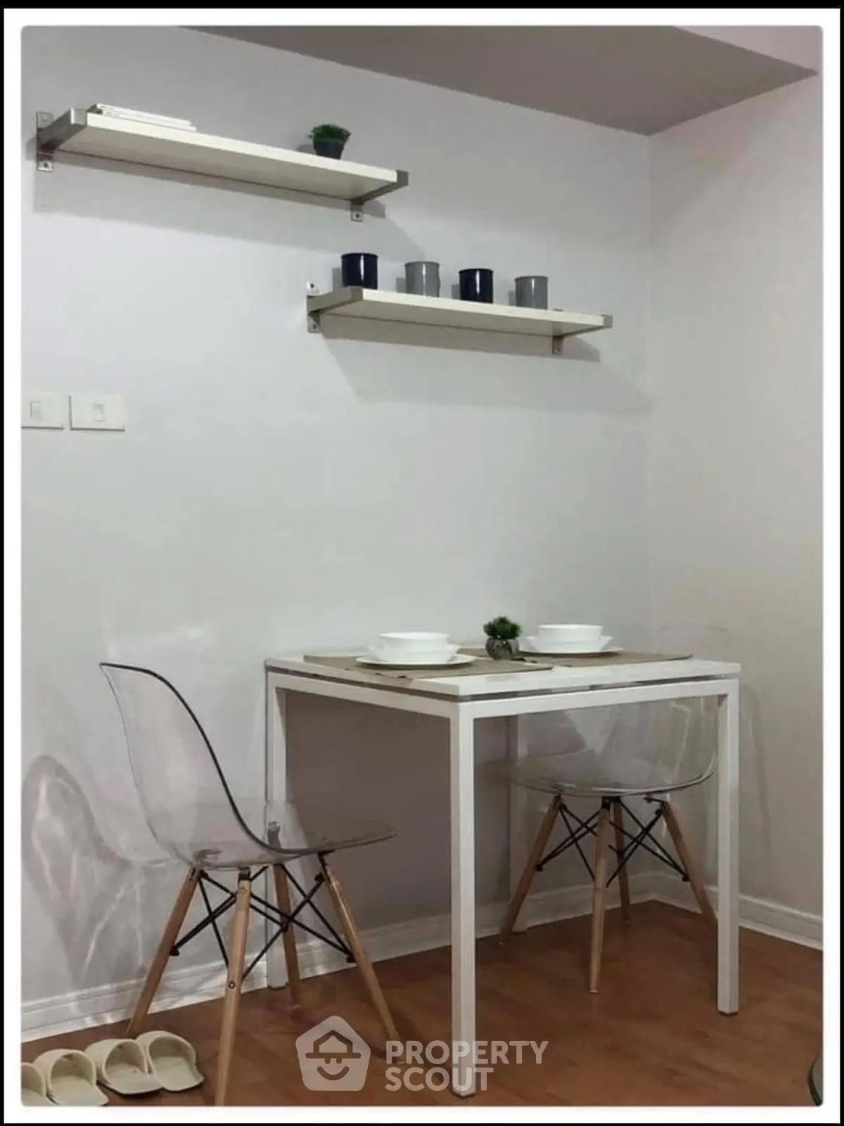 Modern minimalist dining area with sleek white table and transparent chairs, perfect for compact living spaces.