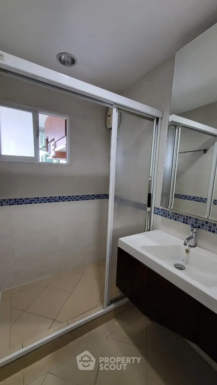 Modern bathroom with glass shower and sleek vanity in contemporary home.