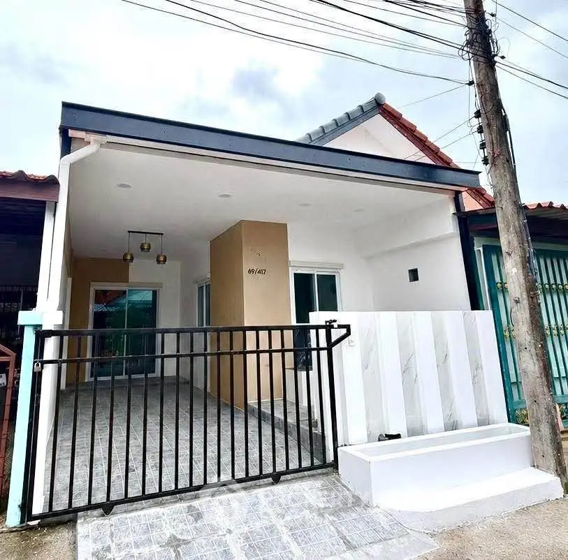 Charming single-story home with modern facade and gated entrance, perfect for cozy living.