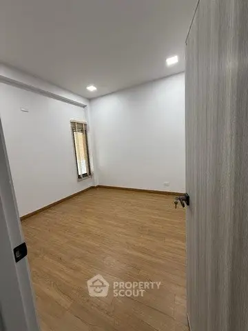 Spacious empty room with wooden flooring and natural light, perfect for customization.