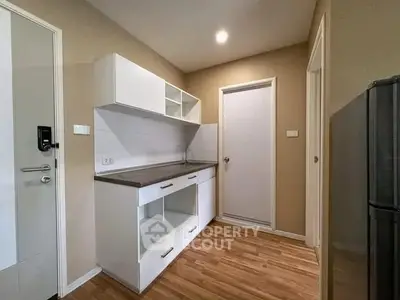 Modern kitchen with sleek cabinetry and wood flooring in a cozy apartment.