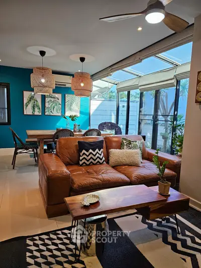 Stylish living room with leather sofa, modern decor, and large windows for natural light.