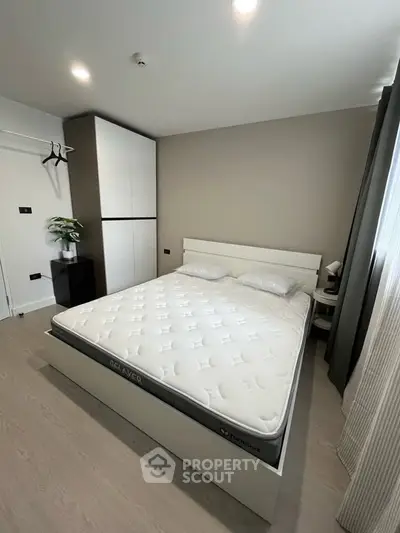 Modern bedroom with minimalist design featuring a comfortable bed and ample natural light.
