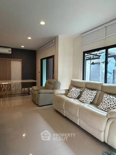 Spacious living room with modern beige leather sofas and large windows for natural light.