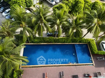 Luxurious aerial view of a serene swimming pool surrounded by lush palm trees and parked cars, perfect for relaxation.