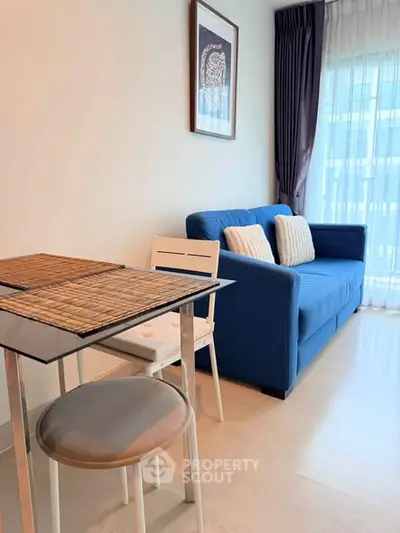 Cozy living room with blue sofa and dining area in modern apartment