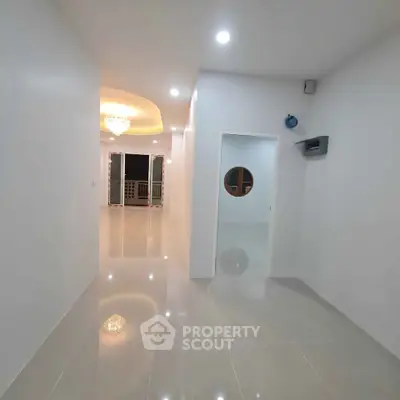 Spacious modern hallway with glossy floors and elegant lighting leading to a bright living area.