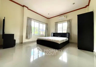 Spacious bedroom with modern furnishings and large windows offering natural light.
