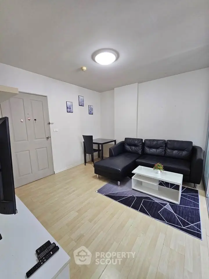 Modern living room with sleek black sofa and stylish decor in a cozy apartment.