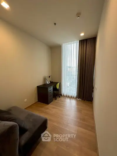 Modern study room with wooden flooring and large window in a contemporary apartment.