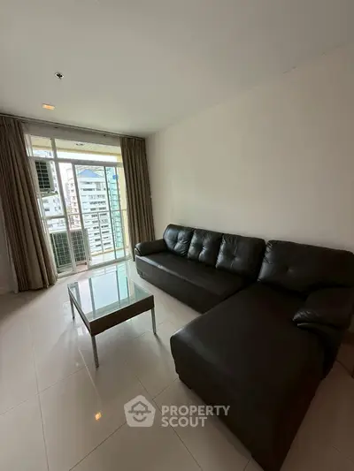 Modern living room with black leather sofa and city view balcony