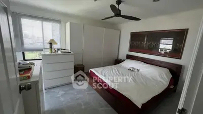 Spacious bedroom with modern decor and large window offering natural light.