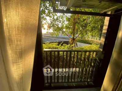Charming balcony view with lush greenery and warm sunlight, perfect for relaxation.