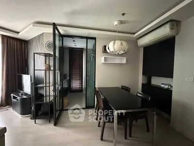Modern living room with dining area and glass partition, featuring sleek furniture and stylish lighting.