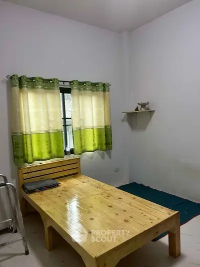 Minimalist bedroom with wooden bed and green curtains, perfect for cozy living.