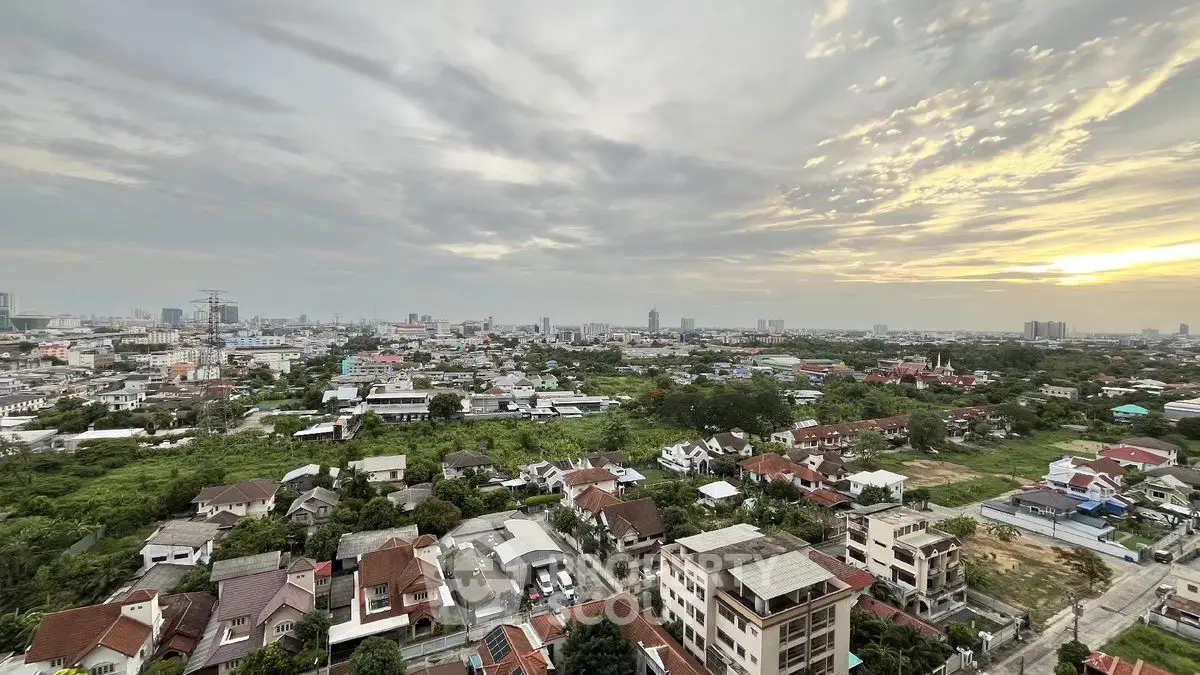Stunning panoramic cityscape view at sunset with lush greenery and urban skyline.